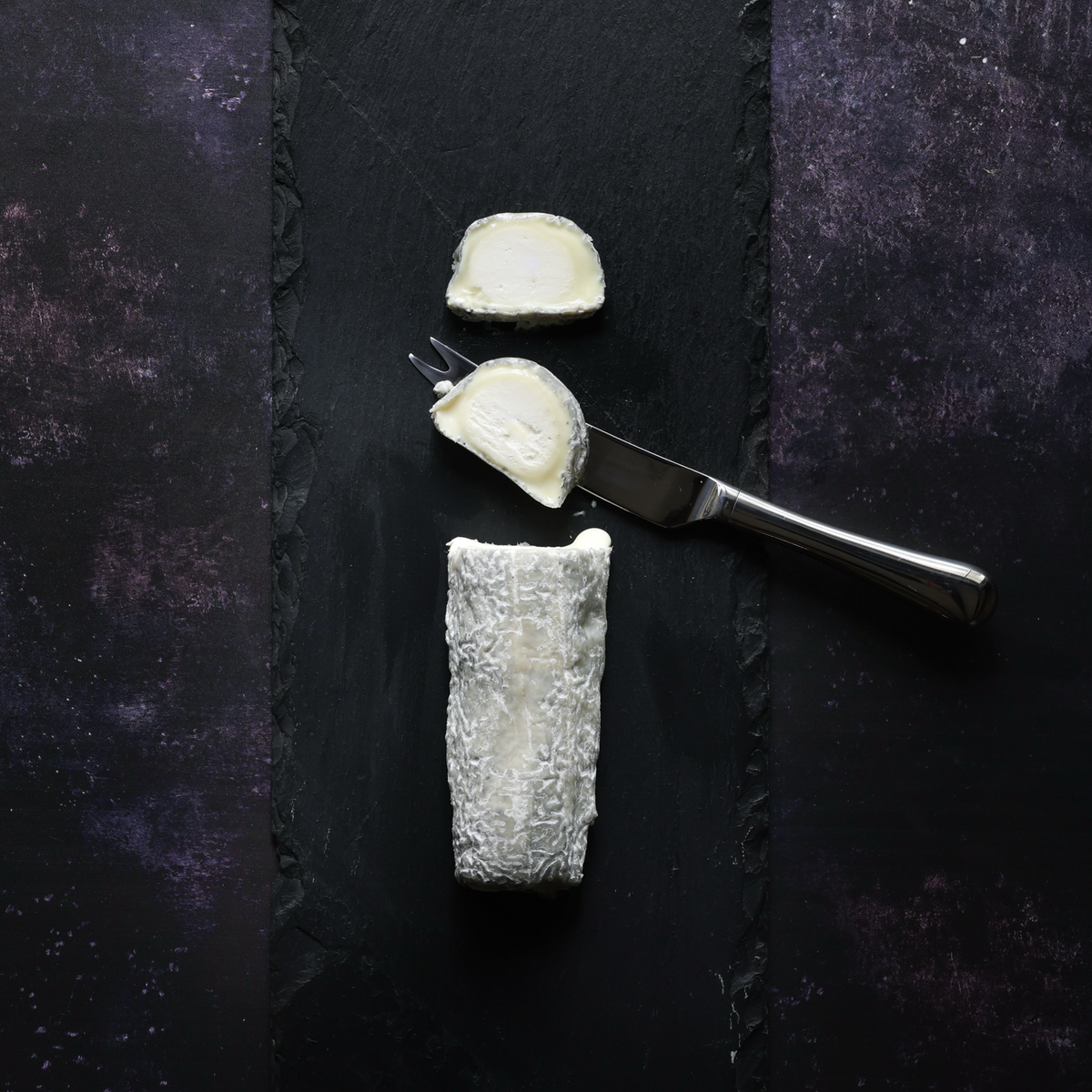 Goat's Cheese Log sliced on a black slate board