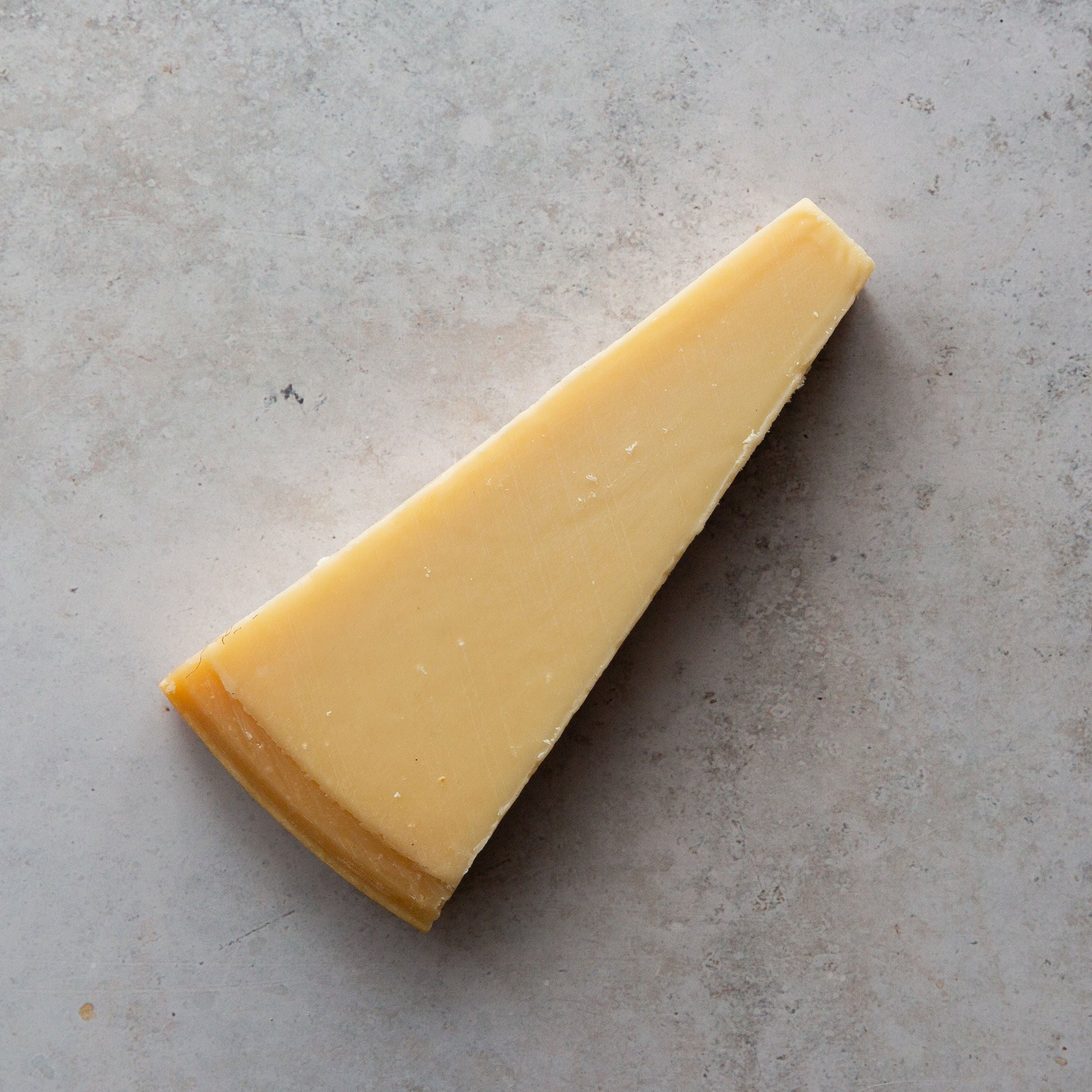 Triangular piece of cheese on a gray surface