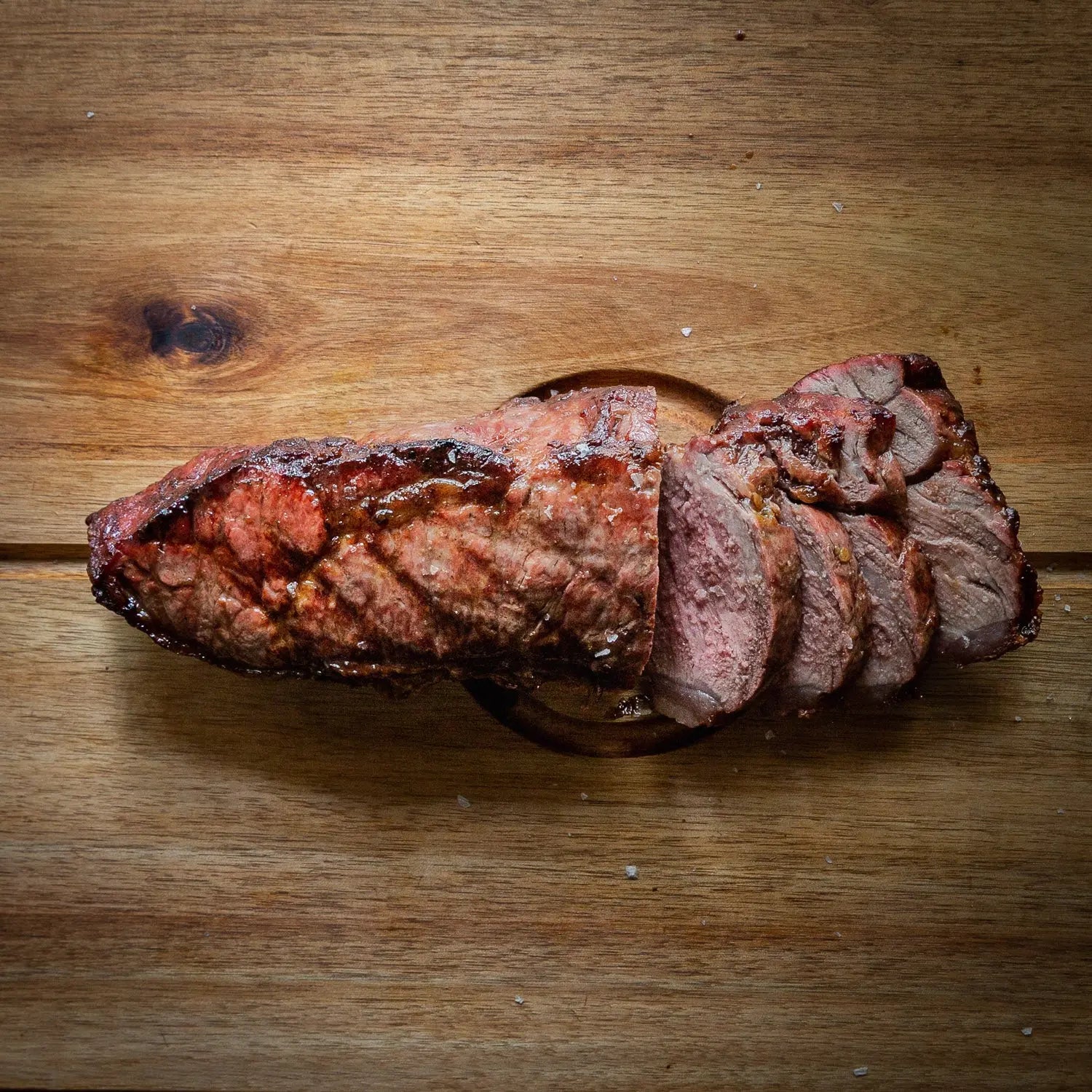 Cooked Sirloin Steak sliced on a wooden board. 